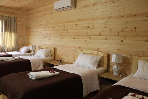 een kamer met drie bedden en een houten muur bij Green Villa Tskaltubo in Tskaltubo