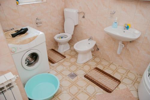 a bathroom with a toilet and a sink and a washing machine at Slobo Apartment in Trebinje