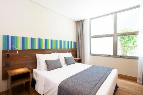a hotel room with a bed and a large window at Prodigy Santos Dumont by Wish in Rio de Janeiro