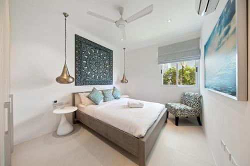 a white bedroom with a bed and a chair at BEACHSIDE VILLA plus APARTMENT - AVA - at SUNSET COVE LUXURY VILLAS, 5 BED 5 BATH, Amazing SEA and MOUNTAIN VIEWS, only 100m walk to Swimming Beach in Bang Rak Beach
