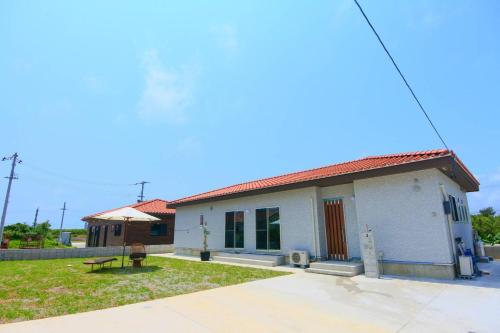 a small white house with a bench in the yard at 2019新築 ! guest house Holoholo beach side in Ishigaki Island