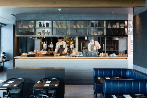 a restaurant with a counter with two chefs preparing food at The Royal Park Canvas - Ginza 8 in Tokyo