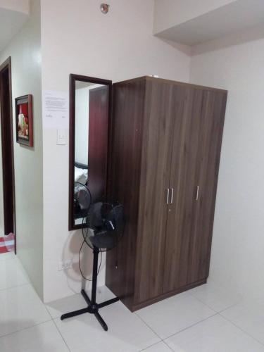 a wooden cabinet with a mirror in a room at Nica's Place Property Management Services at Horizons 101 Condominium in Cebu City