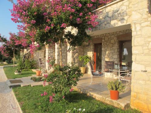 a stone house with a table and pink flowers at Villa Castello Rausch in Poreč