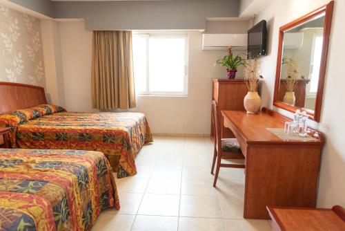 um quarto de hotel com duas camas, uma secretária e um espelho em Hotel Impala -Atras del ADO em Veracruz