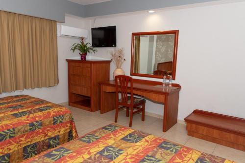 a hotel room with a desk and a mirror at Hotel Impala -Atras del ADO in Veracruz