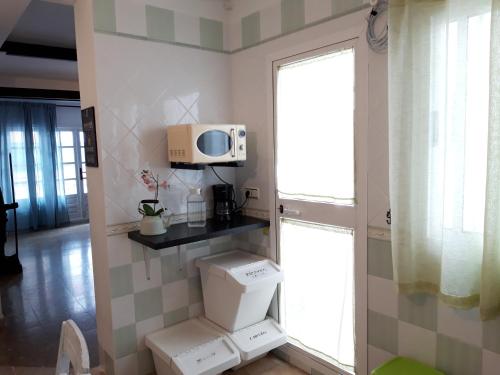 a bathroom with a toilet and a microwave on a wall at Carmen Guest House in Benalmádena