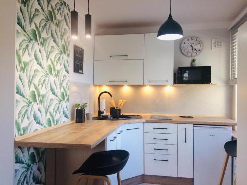 a kitchen with white cabinets and a counter with stools at Apartament Adrianna in Iława