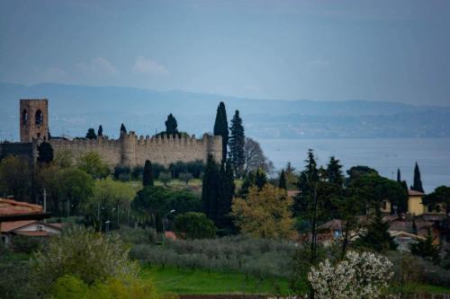 a castle on a hill with trees and a body of water at El Rincon del Artista in Soiano del Lago