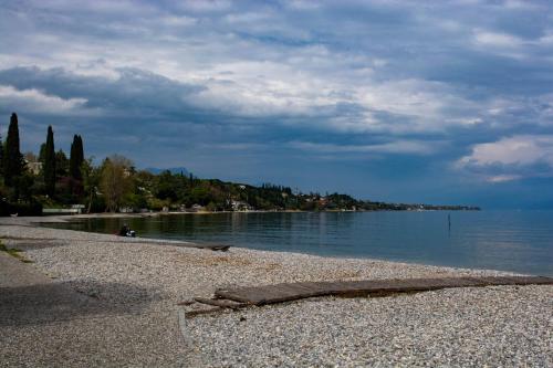 a beach with a rocky shoreline and the water at El Rincon del Artista in Soiano del Lago