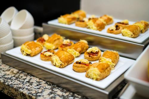 three trays of pastries on plates on a counter at Hotel Best Night in Alger