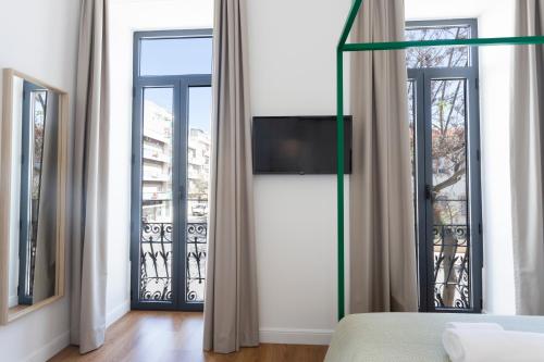 a bedroom with two windows and a tv on the wall at Alameda Exclusive House in Faro