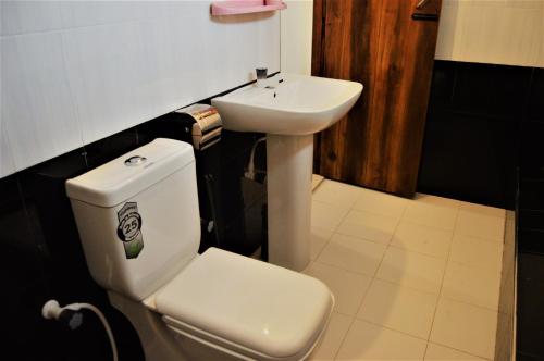 a bathroom with a white toilet and a sink at Shim Beach Resort in Arugam Bay