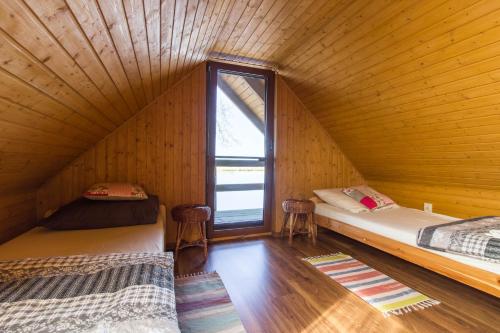 two beds in a wooden room with a window at Domek nad Odrą in Gryfino