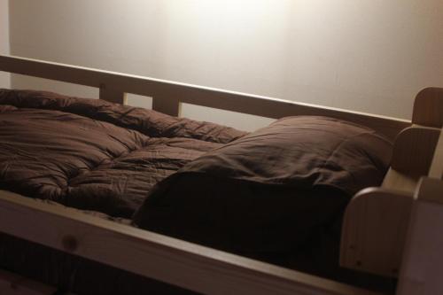 an unmade bed in a bedroom with a light on the wall at Shaq Bighouse in Kanazawa
