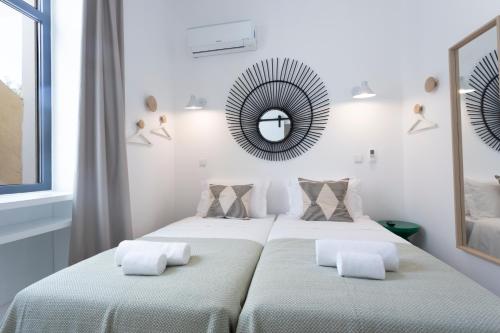 2 Betten in einem weißen Zimmer mit Spiegel in der Unterkunft Alameda Exclusive House in Faro