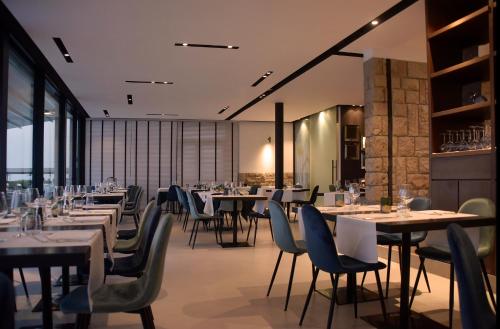 uma sala de jantar com mesas, cadeiras e janelas em Hotel Ril em Lido di Jesolo