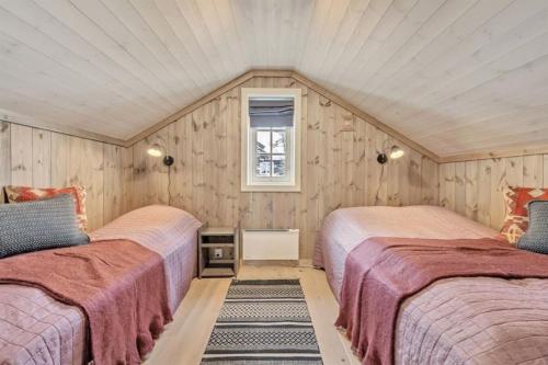 two beds in a room with wooden walls at Kilen Lodge in Gaustablikk
