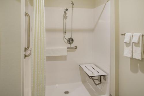 a white bathroom with a shower and a bench at Cobblestone Inn & Suites - Menomonie/UW-Stout in Menomonie