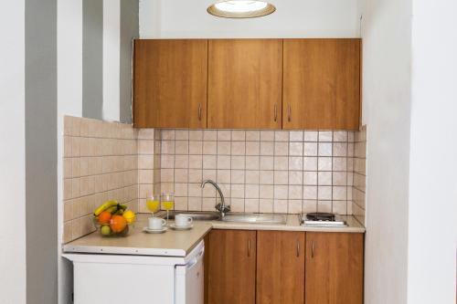 a kitchen with wooden cabinets and a sink at Sunset Apartments in Perdika