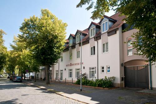 a large white building on a street with trees at Hotel Erfurter Tor in Sömmerda