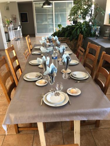 una mesa larga con platos y servilletas. en Le Blockhaus de Domléger et Spa, en Domléger