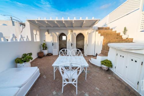 a patio with a white table and chairs and a staircase at Dar el Maq - Antlantic view & Sauna in Asilah