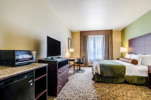 a hotel room with a bed and a flat screen tv at Cobblestone Hotel & Suites - McCook in McCook