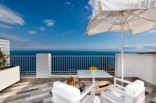 a patio with a white table and chairs and an umbrella at villa orleans in Amalfi