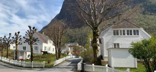 a white house with a fence in front of a mountain at Høyanger 3 roms leilighet in Høyanger