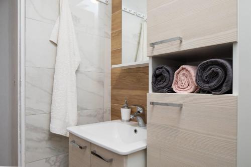 a bathroom with a sink and a shower and towels at Apartments Habek in Vrboska