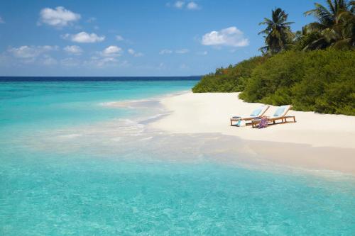 two lounge chairs on a beach near the ocean at Dusit Thani Maldives - 50 percent discount on transfers for stays until 20 Dec 2025 in Baa Atoll