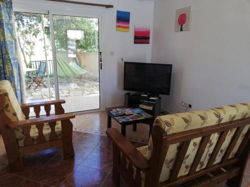 a living room with a couch and a television at Chriselina Gottage in Paphos