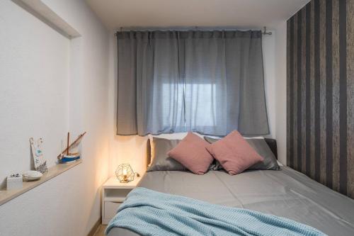a bedroom with a bed with pink pillows and a window at Apartments Habek in Vrboska