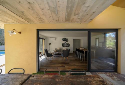 a dining room and living room with sliding glass doors at Hôtel confidentiel Le Grecale in Pianottoli-Caldarello