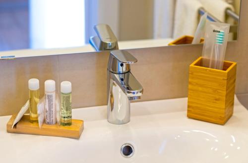 a bathroom sink with a faucet and two bottles of toothpaste at Taormina Bedda Rooms in Taormina