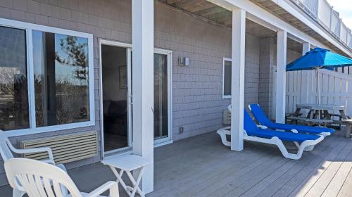 a porch with chairs and an umbrella and a table at Sea Crest in Amagansett