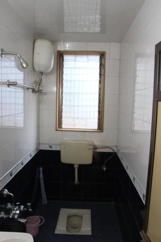 a bathroom with a toilet and a sink and a window at Ladakh House- 3 BHK Ladakh themed Villa near Matheran in Neral