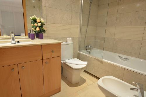 a bathroom with a toilet and a sink and a tub at Saval Spa Aqquaria Family Complex in Salou