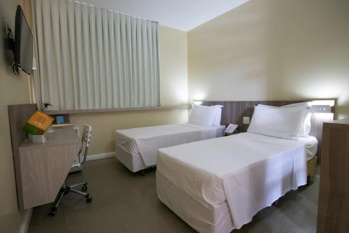 a hotel room with two beds and a window at Slim Cuiabá Aeroporto in Cuiabá