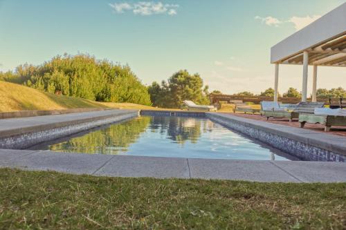 a swimming pool in a park with two benches at Posada Azul Marino in José Ignacio