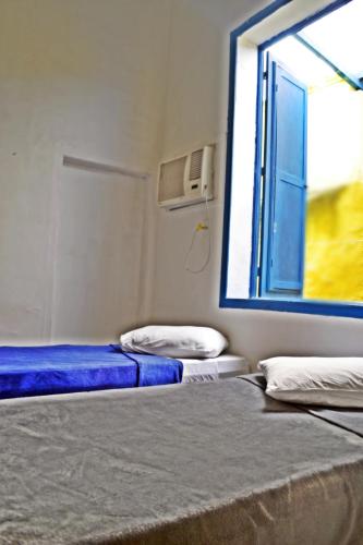 two beds in a room with a window at Brasileranza Hostel in Niterói