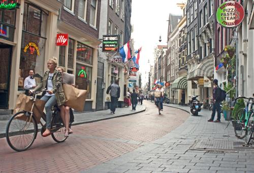 a woman riding a bike down a city street at Koopermoolen in Amsterdam