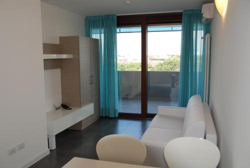 a living room with a white couch and a window at Aparthotel Tiziano in Grado