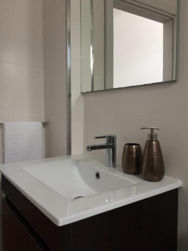 een badkamer met een witte wastafel en een spiegel bij Retiro dos Reis in Horta