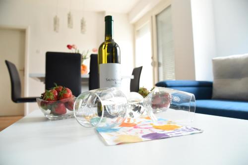 a bottle of wine and glasses on a table at Kiara Apartments Skopje in Skopje
