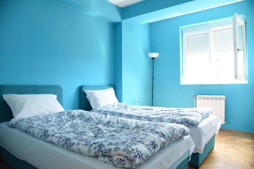 a blue bedroom with a bed with a blue wall at Kiara Apartments Skopje in Skopje