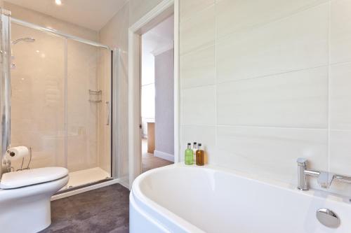 a bathroom with a tub and a toilet and a shower at The Glen Guest House in Kendal