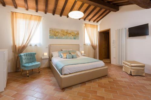 ein Schlafzimmer mit einem Bett und einem blauen Stuhl in der Unterkunft Casa Vacanze Montefalco Il Borgo in Montefalco