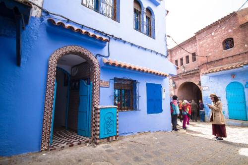 a group of people standing outside a blue building at Résidence chaounia d'hote in Chefchaouene